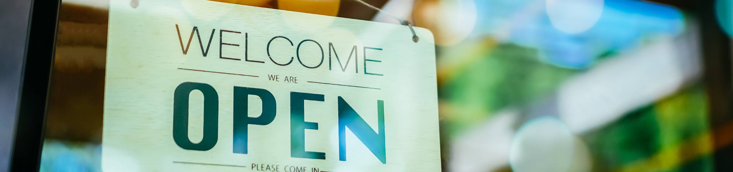 Business sign that says “Welcome – we are open – please come in.” for a local small business
